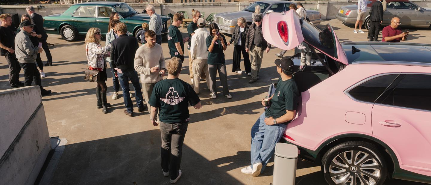 a gathering of motoring enthusiasts near a pink Bentley Bentayga