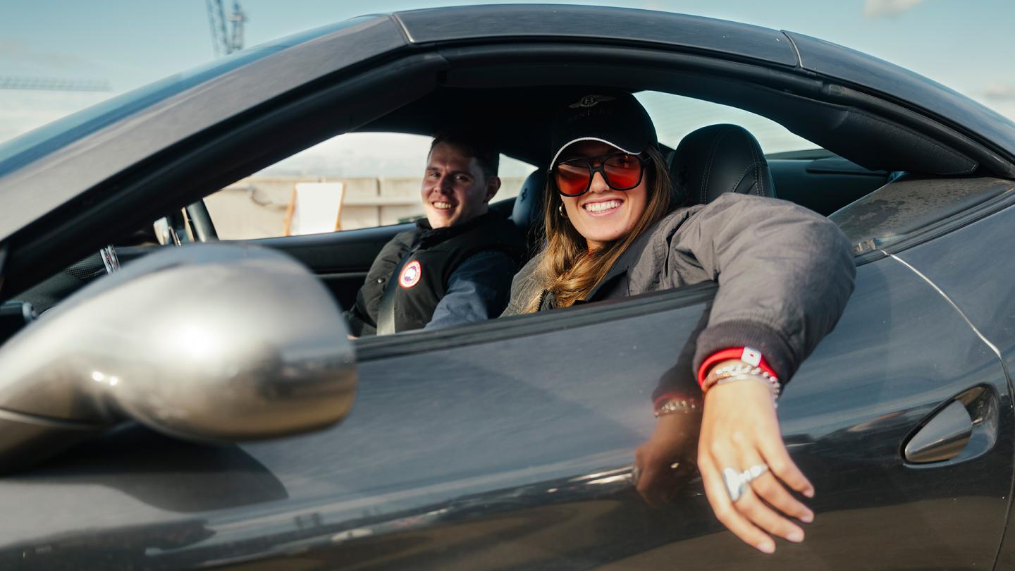 People sitting smiling in front seat of Bentley car