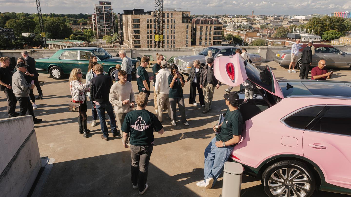 Pink Bentley Bentayga with Bentley customers and car enthusiasts talking with cars behind them