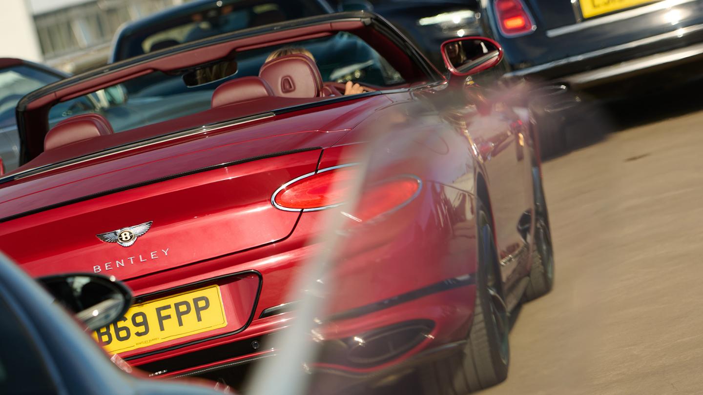 Red Bentley convertible amongst other parked cars