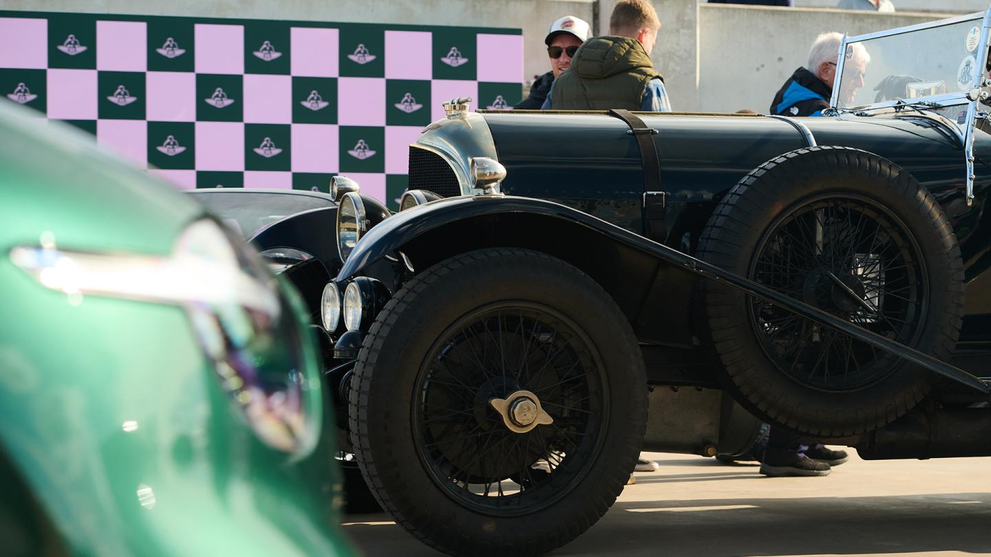 Bentley Blower heritage car with people behind it, new green Bentley car headlight in foreground